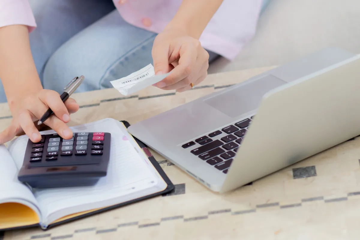 Mains sur une calculatrice et un ordinateur portable, budget du foyer