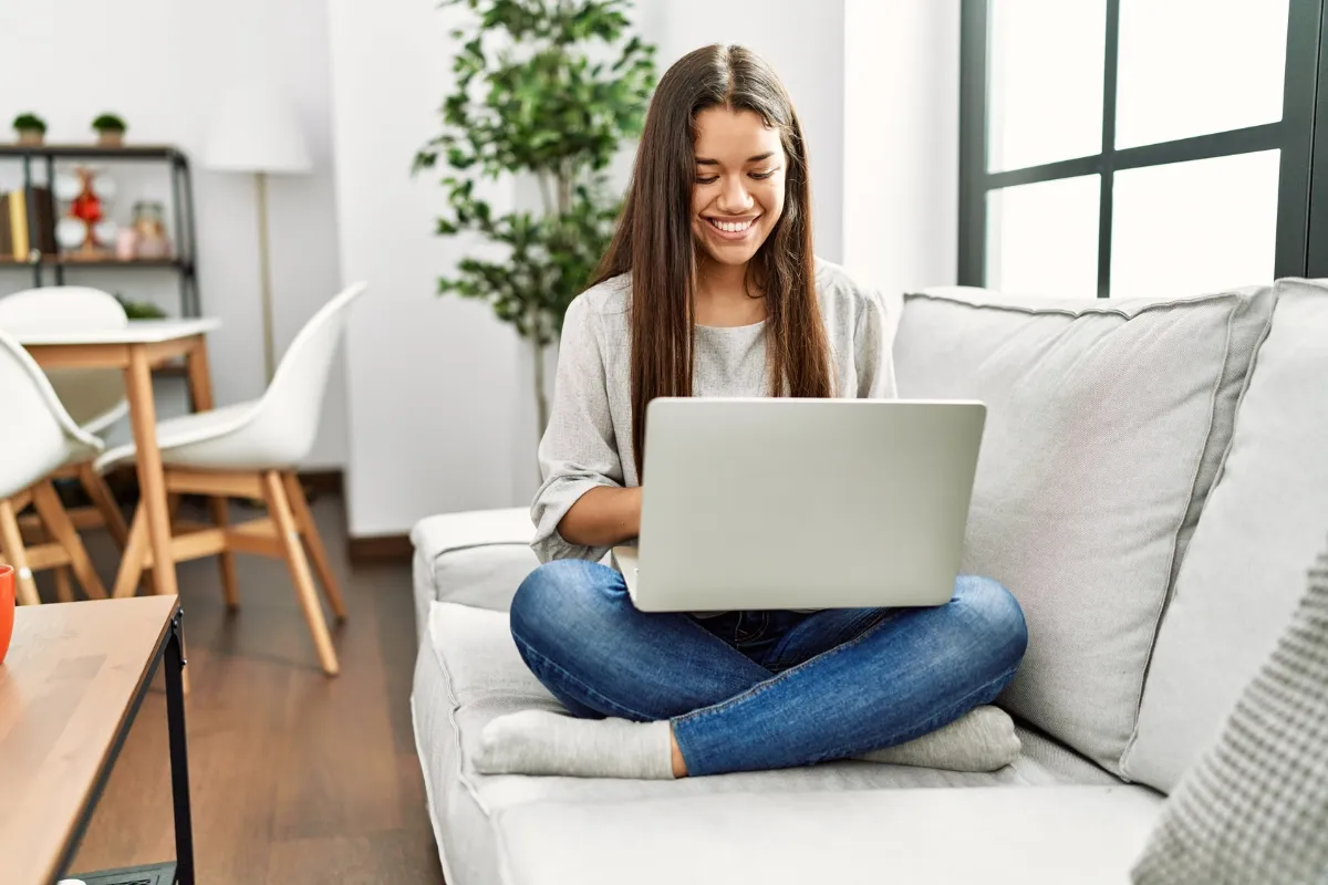 Jeune femme consultant son ordinateur portable dans son salon