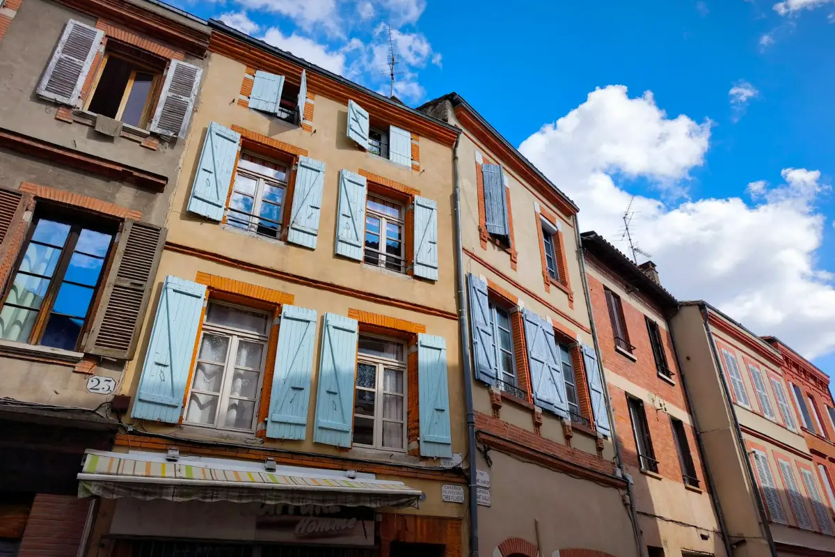 Façades anciennes aux volets bleu clair dans une rue de Toulouse