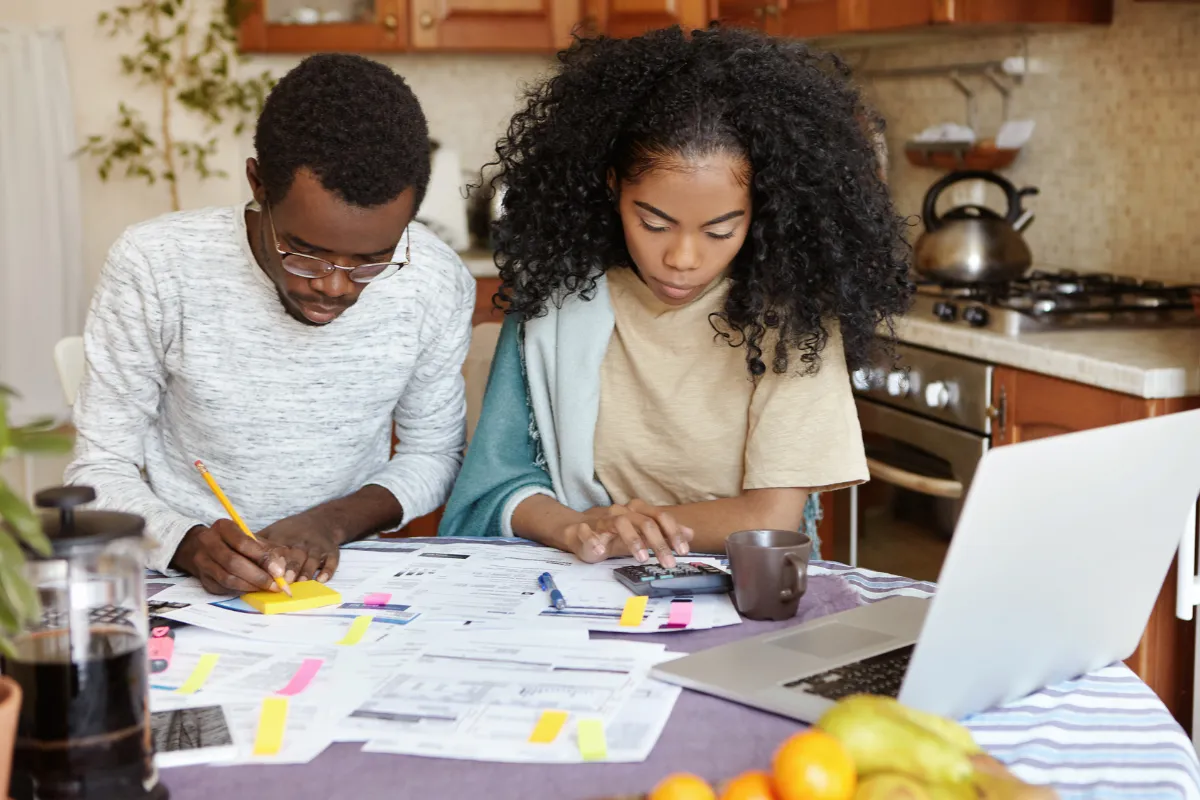 Couple faisant ses comptes à la table de la cuisine, papiers et calculatrice